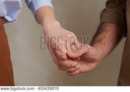 Close-up Studio Shot Of Unrecognizable Affianced Man And Woman Tenderly Holding Their Hands
