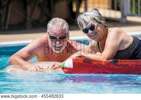 Happy Retired Senior Caucasian Couple Enjoy Together The Summer With An Active Lifestyle At The Pool