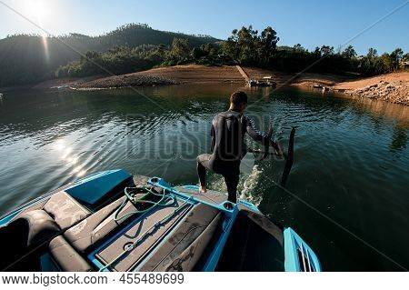 Rear View Of A Man In A Wetsuit With A Foil Wakeboard In His Hands