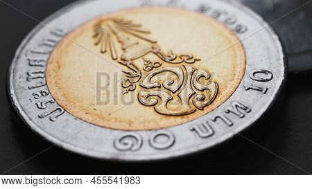 Translation: 10 Baht Thailand. Thai Coin Of 10 Baht Lies On Dark Black Surface. Economy Or Finance. 