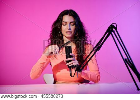 Stylish Young Caucasian Female Influencer Sitting At Desk In Studio Recording Sounds Made With Hair 