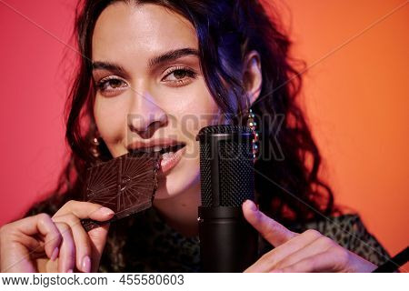 Horizontal Close-up Of Young Caucasian Woman Sitting In Studio In Pink And Orange Neon Light Recordi