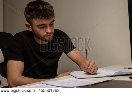 A University Aged Male Student Doing Coursework At A Desk