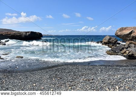 Frollicking Waves On Black Stone Beach On The Coastline Of Aruba.