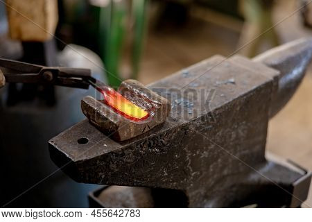 Close Up View Of Heated Metal And Anvil. The Blacksmith In The Production Process Of Metal Products 