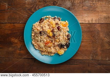 A Large Dish Of Couscous With Dried Fruits, Saffron And Nuts On A Wooden Table. Horizontal Photo