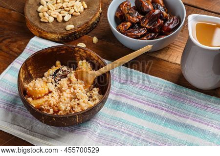 A Plate Of Couscous With Dried Fruits And Nuts On A Wooden Table On A Napkin With A Wooden Spoon. Ho