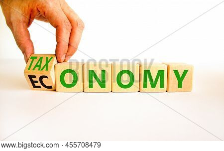 Taxonomy Or Economy Symbol. Businessman Turns Wooden Cubes And Changes The Concept Word Economy To T