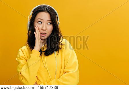 Let Me Tell A Gossip. Shocked Cute Asian Student Young Woman In Yellow Hoodie Sweatshirt In Headphon