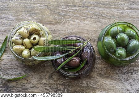 Salted Olive Fruits In Glass Jar Over Wooden Background. Mediterranean Food.
