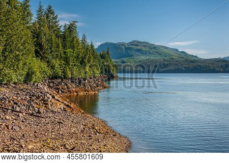 Ketchikan, Alaska, Usa - July 17, 2011: Landscape, Dense Green Forests Above Brown Rocky Shoreline A