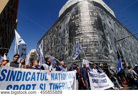 Bucharest, Romania - April 06, 2022: Protesters At A Union Rally Pass By An Advertisement For Untold
