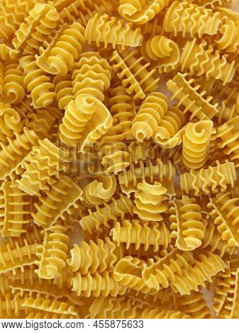 Dry Curly Pasta Closeup. Pasta Made Of Durum Wheat Top View. Yellow Unboiled Macaroni Background.