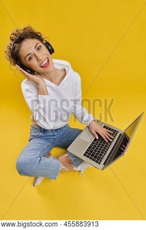 Pretty Caucasian Woman Listening To Music On Laptop In Studio. Above View Of Young Girl In Hoodie Si