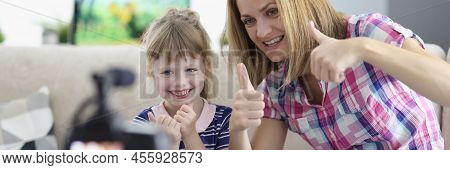 Portrait Of Mother And Daughter Showing Thumbsup On Video, Videocamera Set On Tripod. Little Girl An