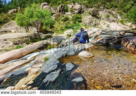 Man Sitting On Some Rocks And Surrounded By Water, Streams And Waterfalls.