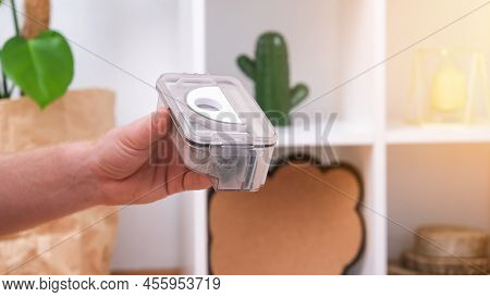 A Man Shakes Out A Garbage Container From A Robot Vacuum Cleaner. The Container Is Full Of Wool, Dus