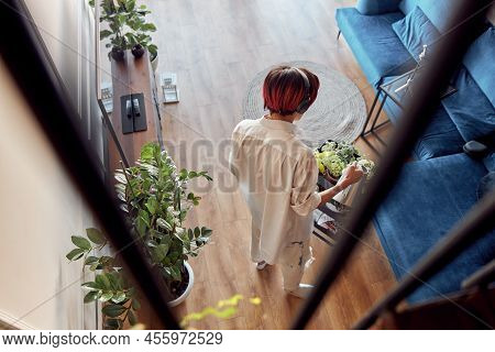 Guy In Headphones Watering Green House Plant At Home