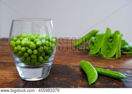Green Peas In Glass Bowl. Fresh Pea In The Pod With Green Leaves. Green Peas On A Brown Wodden Table