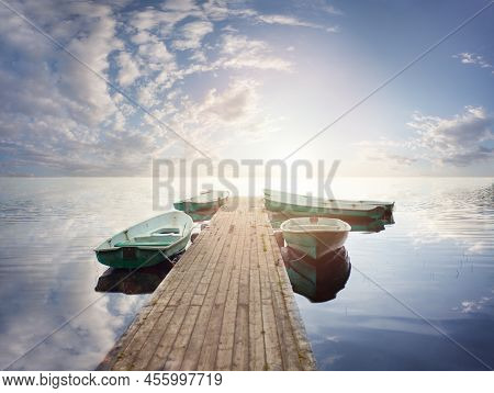 Small Wooden Dock And Boats At The Lake Against Sky Clouds Background