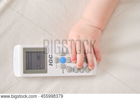 Baby Toddler Boy Holds The Air Conditioner Igc Remote Control In His Hand. Child With Remote Control