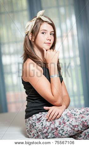 Beautiful teen girl lying on bed and looking at camera.Image of pretty teenager posing indoor