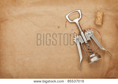 Cork and corkscrew with red wine stains on brown paper background with copy space