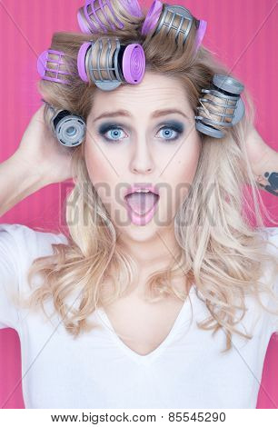 Young attractive surprised blonde woman with hot rollers beauty concept