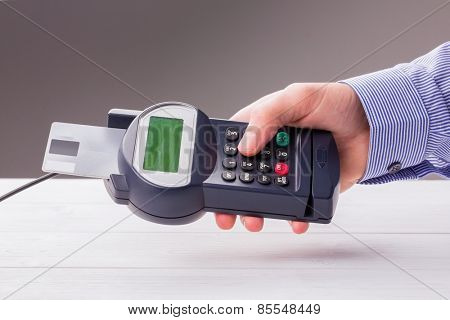 Man entering his pin on terminal on a wooden table
