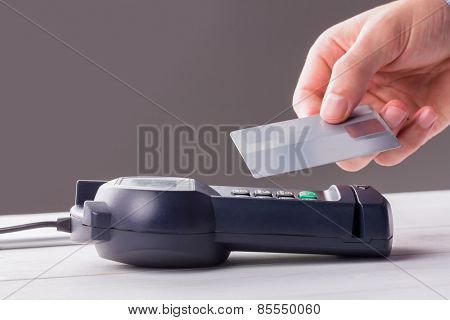 Man using card to express pay against grey background
