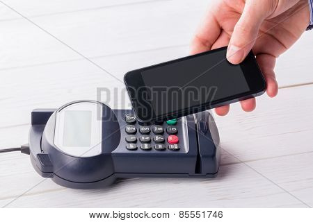 Man using smartphone to express pay on a wooden table