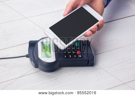 Man using smartphone to express pay on a wooden table
