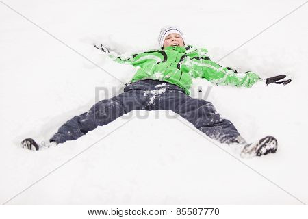 Young Boy Playing In Snow Lying On His Back