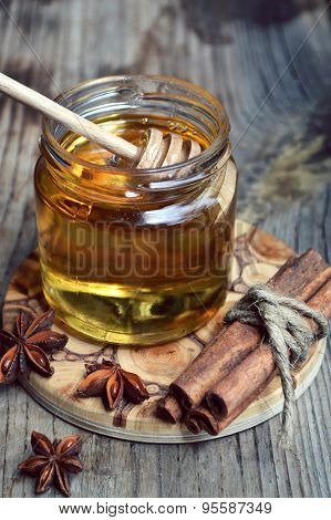 Golden honey with honeystick. cinnamon and anise stars on wooden table