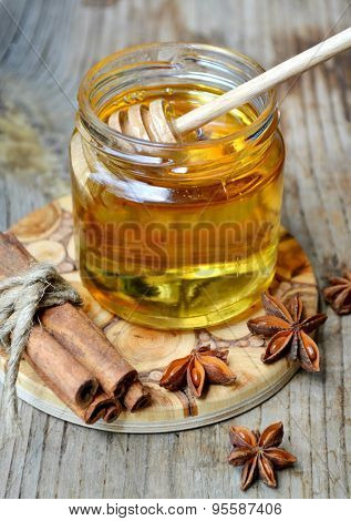 Golden honey with honeystick. cinnamon and anise stars on wooden table