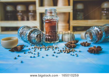 Glass shakers with seasoning on wooden background