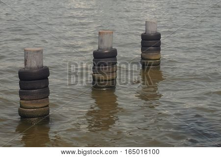 boat bumper metal pillar in the river near pier made by old ties