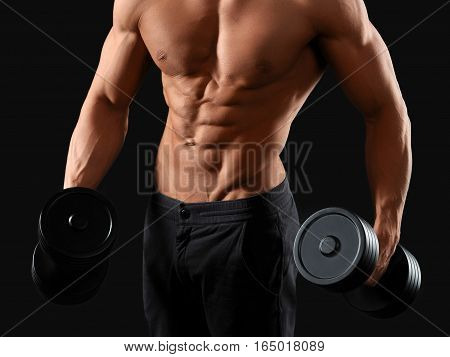 Sport is a lifestyle. Cropped studio shot of a ripped man working out with dumbbells against black background