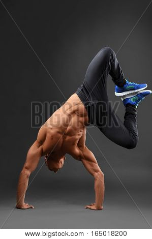 Staying active. Full length portrait of a shirtless strong man doing a handstand against grey background