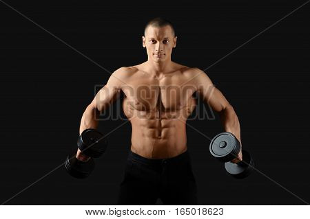 Broadening his back. Studio shot of an attractive young shirtless man pumping iron showing off his ripped abs