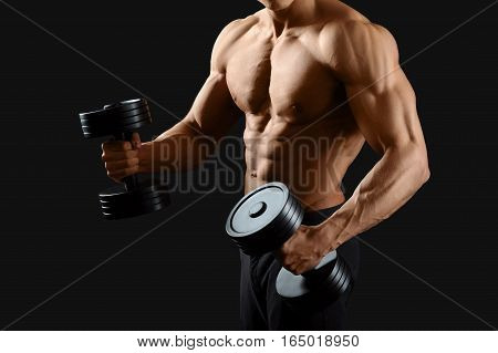 Powerful body. Cropped shot of a sexy hot male posing shirtless with dumbbells on black background