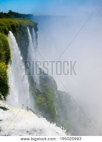 Close view from one of the water falls in Cataratas del Iguazu park, with a blue sky and a lot of water in the air, misty.