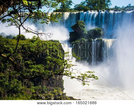 Vew of the water falls in Cataratas del Iguazu park, with a blue sky and a lot of water in the air, misty, rainow.