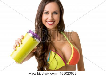 Healhy lifestyle concept. Athletic woman in bright bikini holding shaker with protein cocktail and looking to camera with smile isolated on white background, studio shot