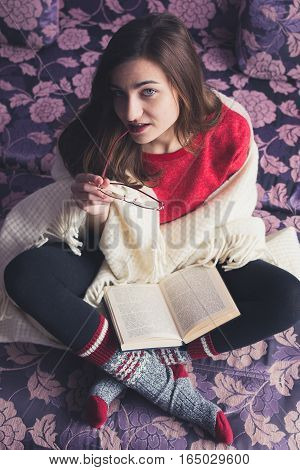 girl reading a book in a warm blanket