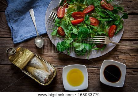 fresh mix of lettuce salad with tomato and a can of sardines in olive oil