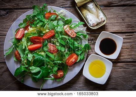 fresh mix of lettuce salad with tomato and a can of sardines in olive oil