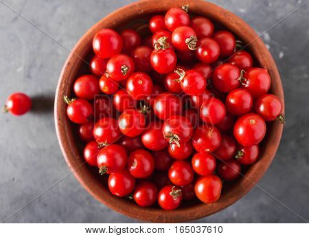 Cherry tomatoes in a clay bowl. Colorful tomatoes Tomatoes background. Fresh tomatoes Healthy food concept. Colorful festive still life. Loosely laid tomatoes in different positions. Copyspace