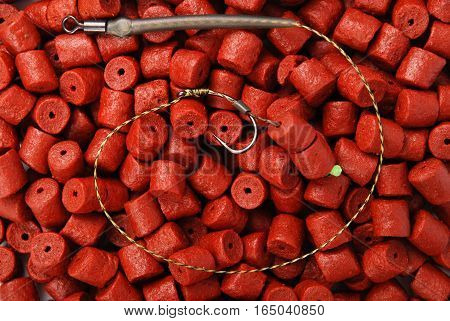 Fishing bait with hook on red pre-drilled halibut pellets for carp fishing background