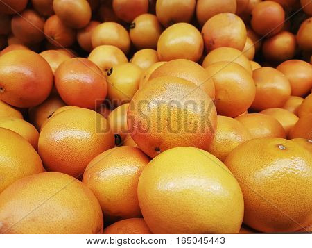 Full frame view of orange grapefruits stacked together on display shelves for sale